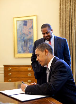 Joshua DuBois, director of the White House Office of Faith Based Initiatives, looks on as President Barack Obama signs the proclamation marking the National Day of Prayer in the Oval Office of the White House May 7, 2009. Official White House Photo by Pete Souza